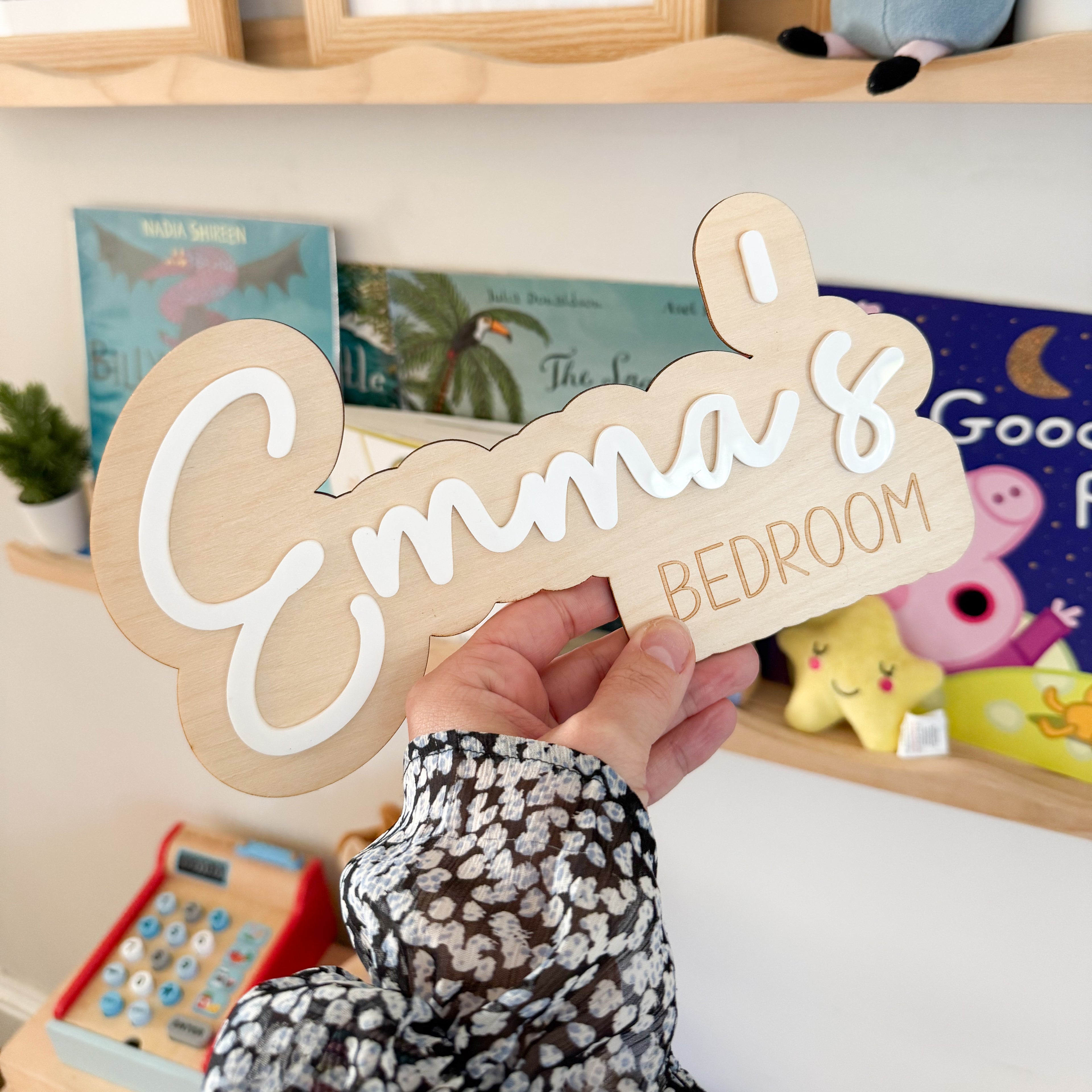 A person is holding a wooden sign that says "Emma&