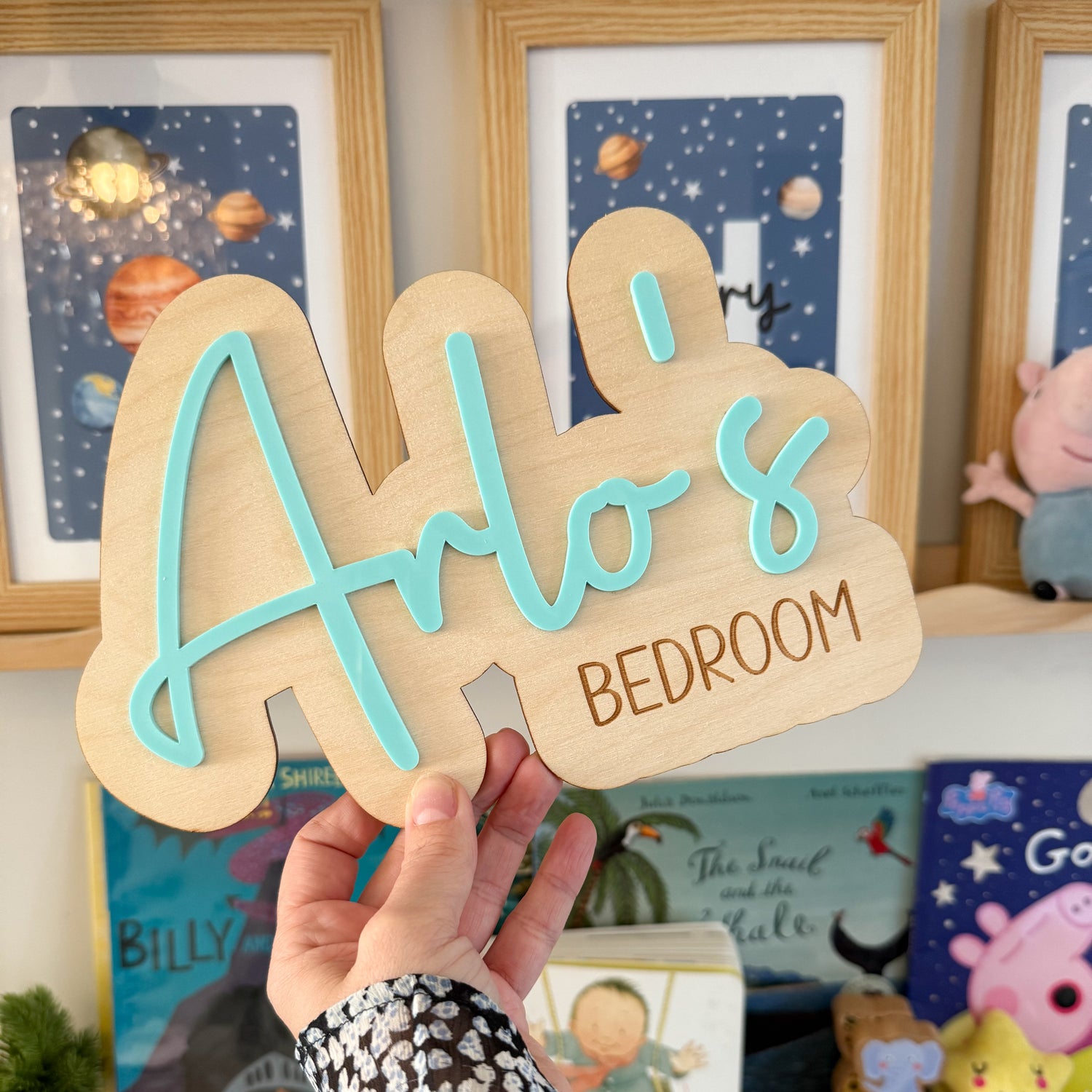 A hand is holding a wooden sign with the name &quot;Arlo&
