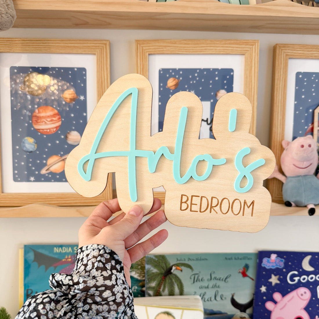 A hand holding a wooden sign with the name &quot;Arlo&