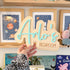 A hand holding a wooden sign with the name "Arlo&